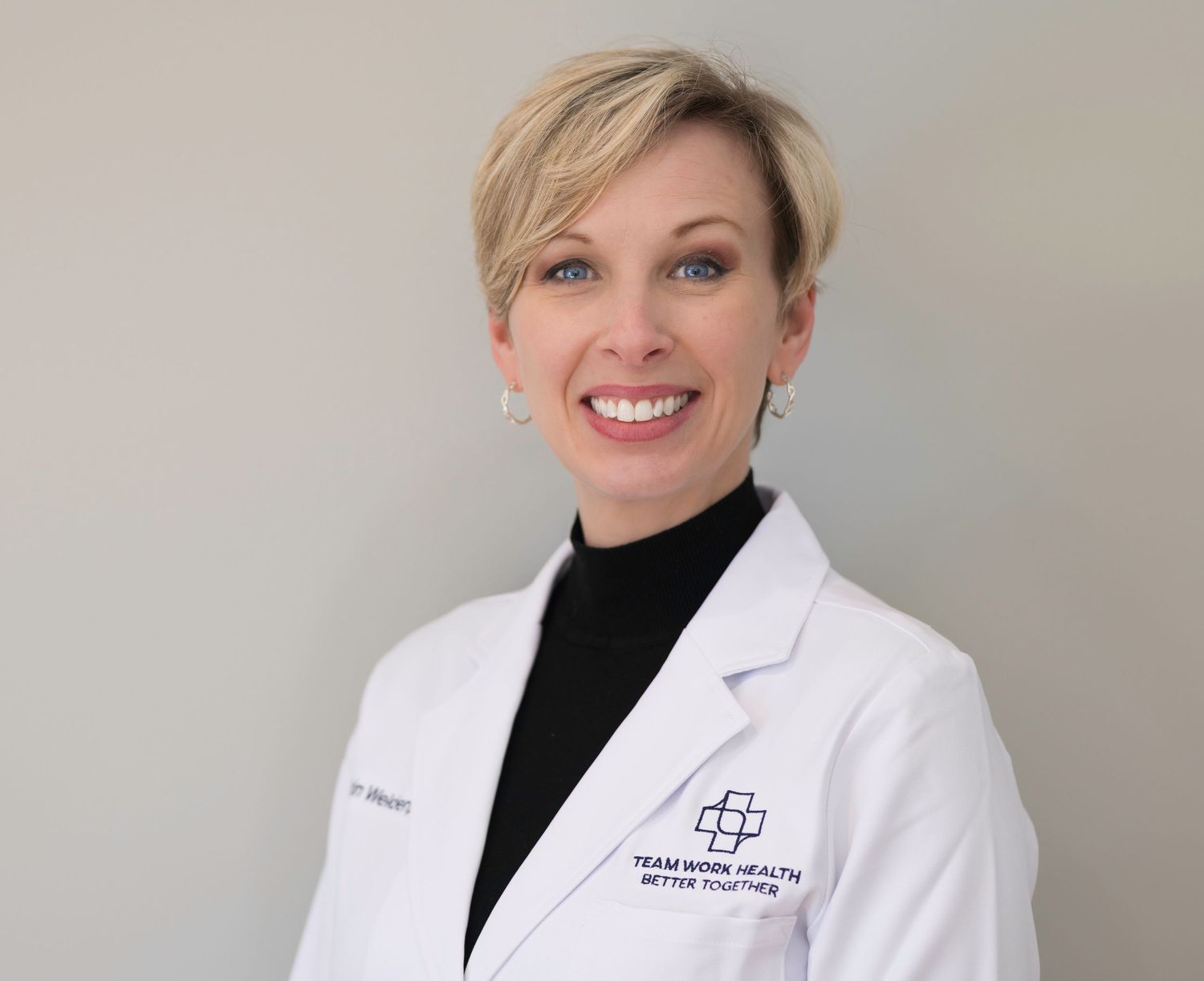 Professional medical headshot of a female healthcare provider in a white coat