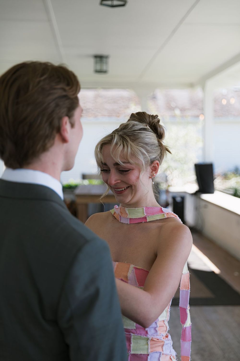 Emotional bridesmaid in colorful dress crying happy tears during a heartfelt moment at a wedding.