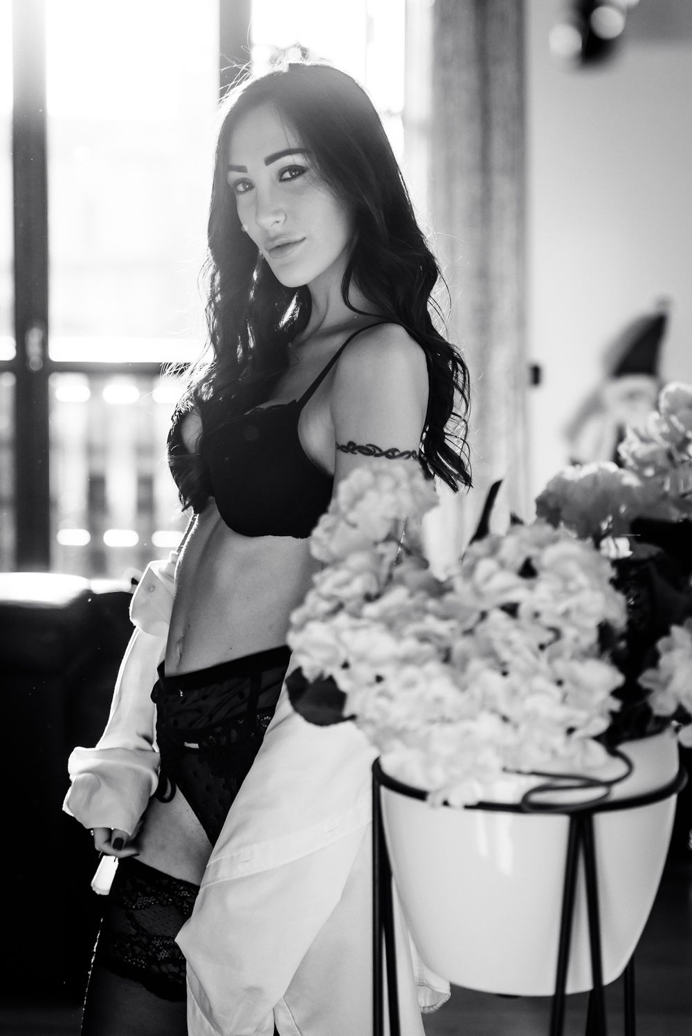 Ritratto boudoir e glamour di una modella in intimo nero e camicia bianca sbottonata.
