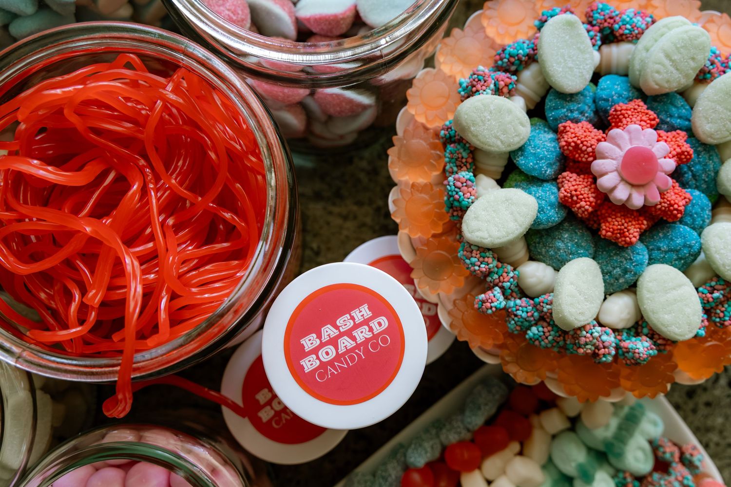 Colorful candy display with red licorice, gummy sweets, and a Bash Board Candy Co. label at a candy buffet.