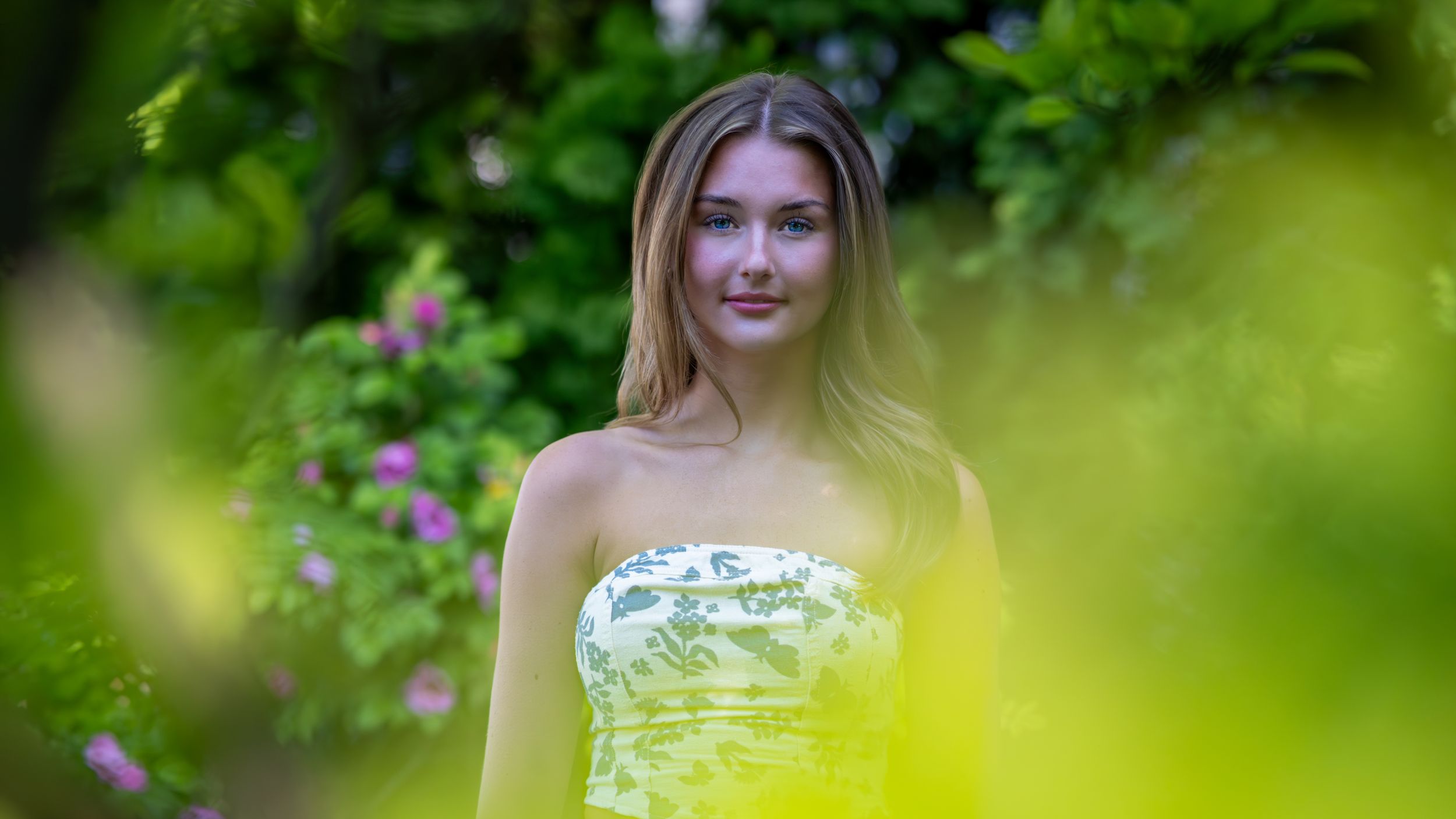 Creative portrait of a young woman framed by green foliage
