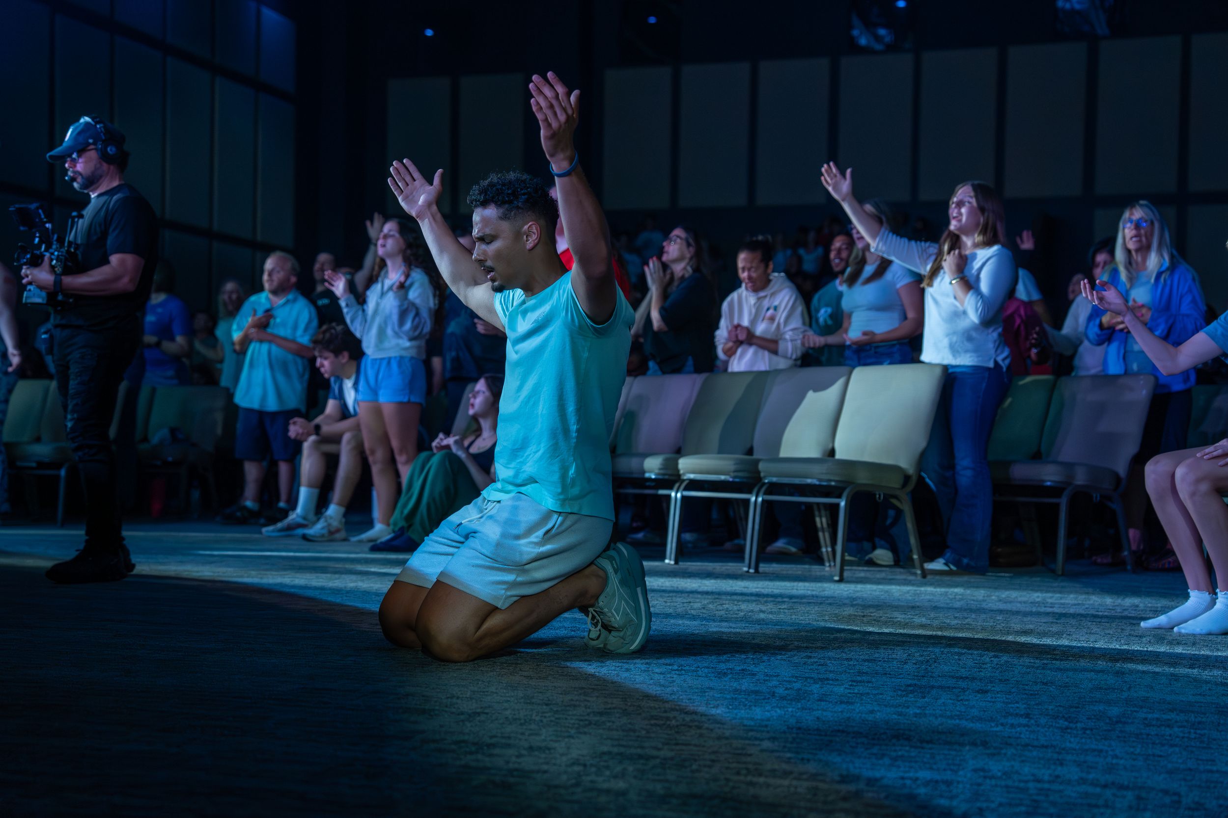 Man kneeling on stage during a Night of Worship event with congregation behind