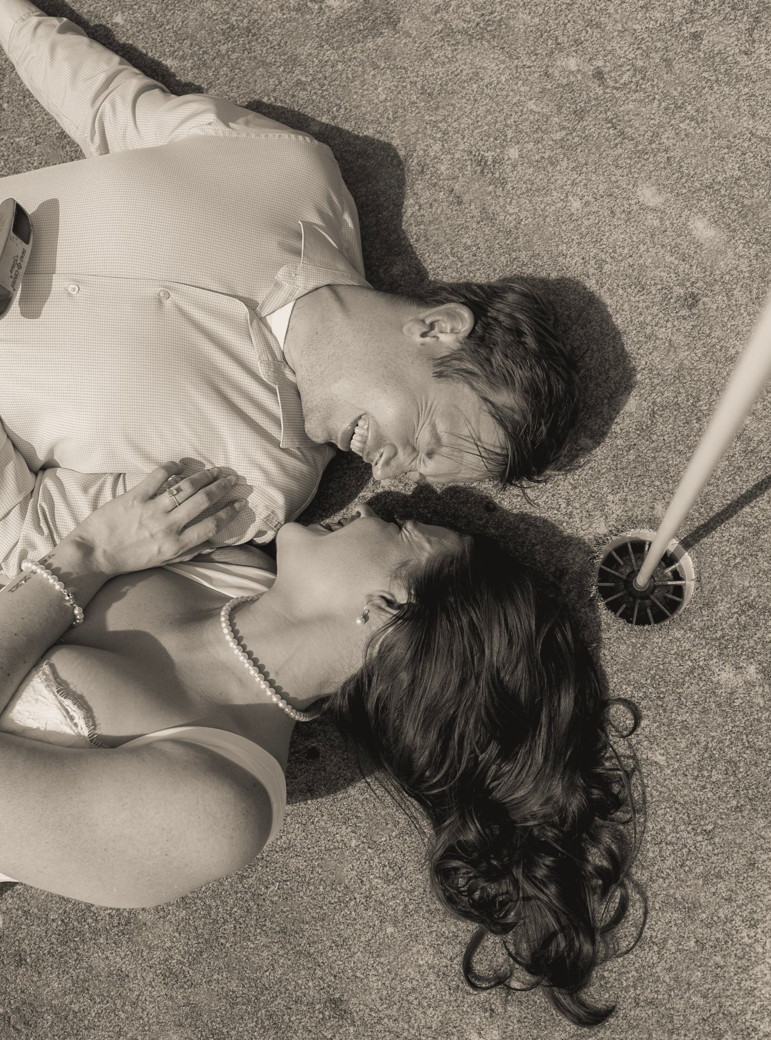 Romantic black and white photo of couple lying on ground gazing at each other lovingly.