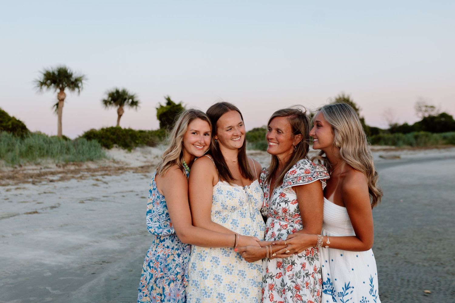 Bridesmaids holding orange Clemson football jerseys while wearing white dresses and nude heels on green grass.