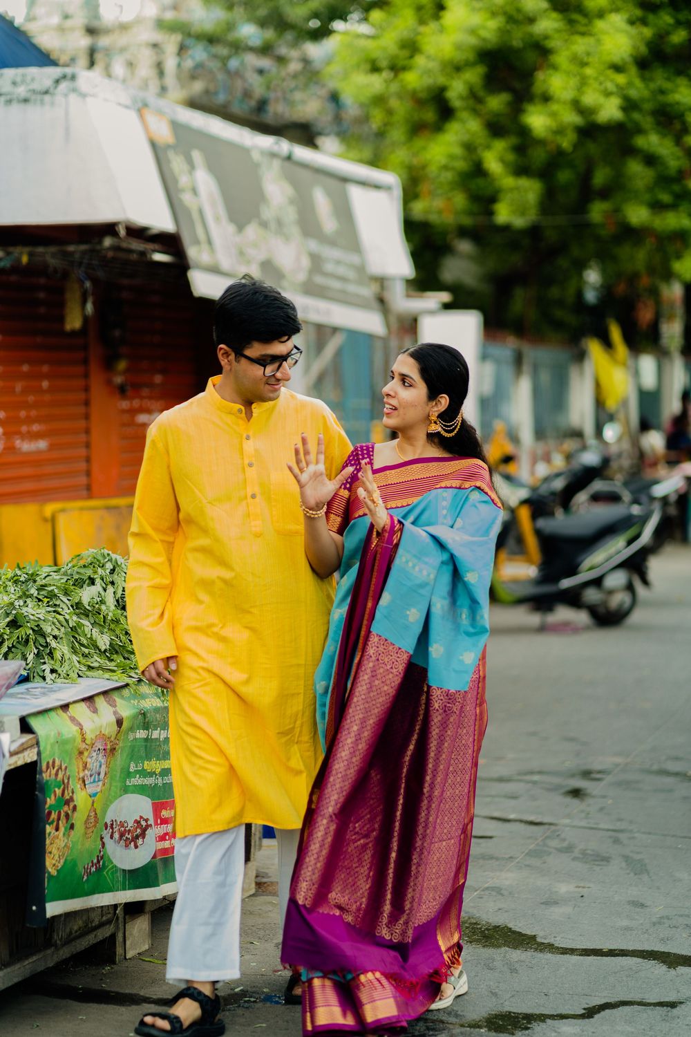 Indian couple in traditional attire, yellow kurta and silk saree, walking on street.