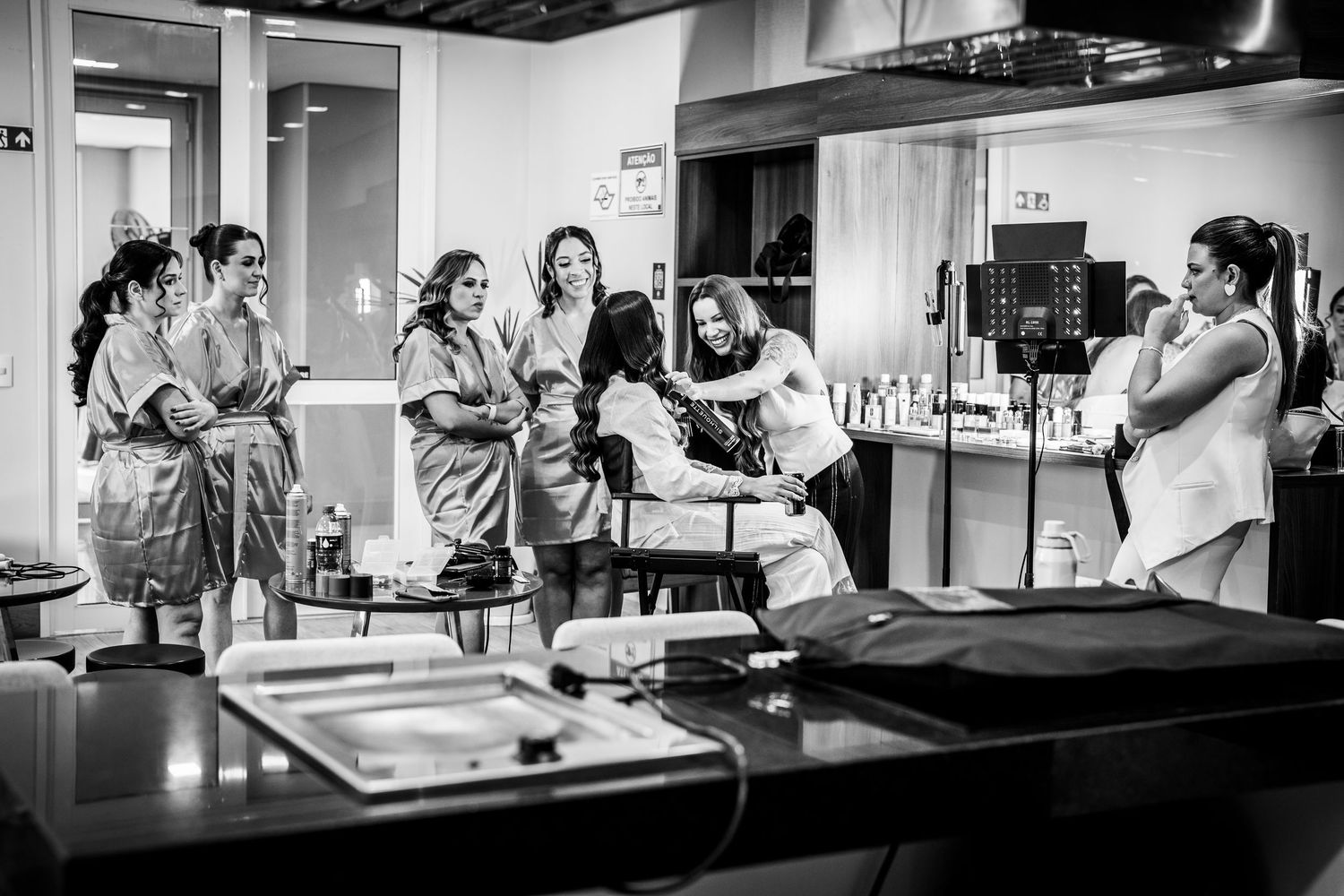 Bridesmaids in robes laugh together during bridal preparations in a getting-ready suite.