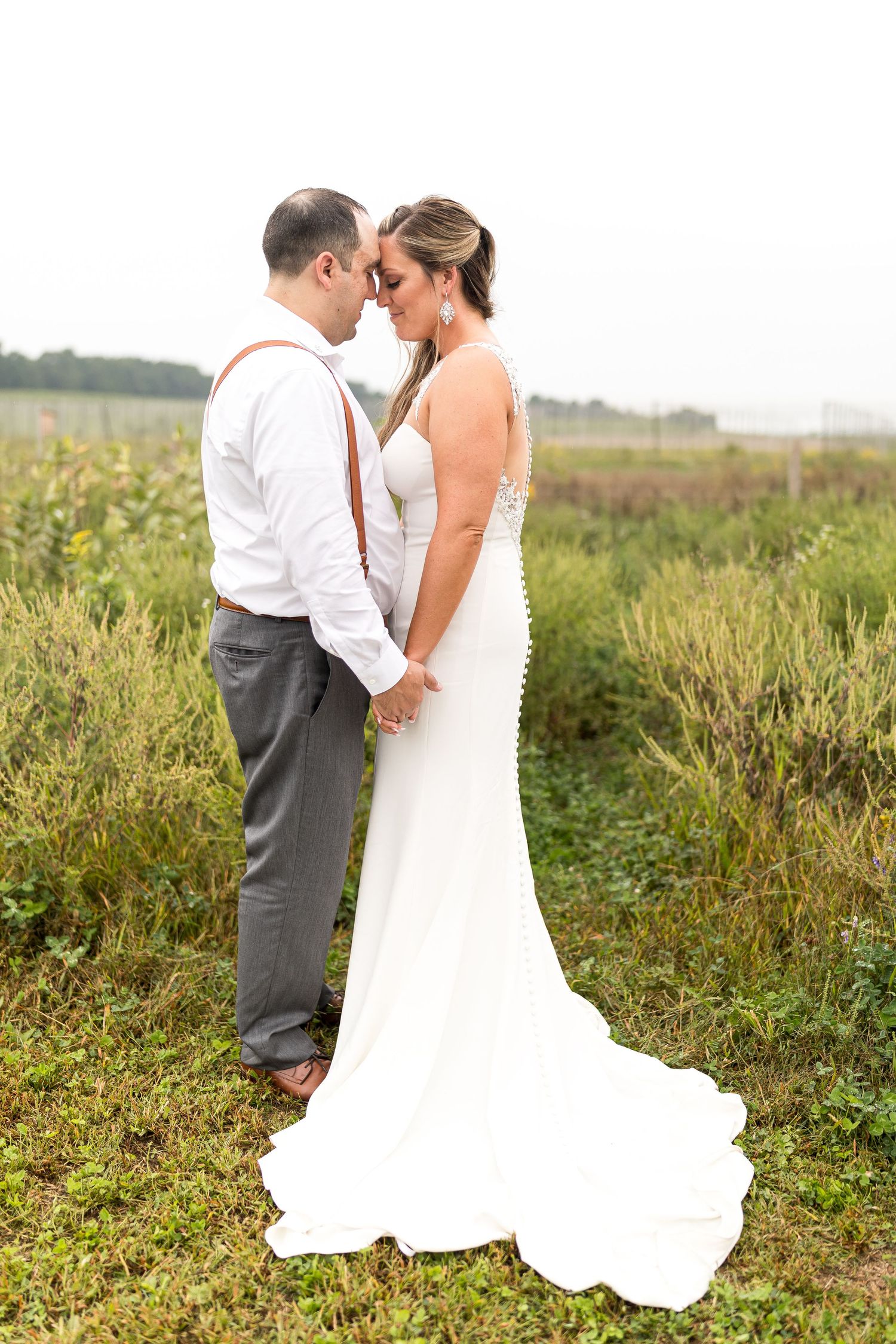 A romantic moment between newlyweds in an open field with flowing white wedding dress.