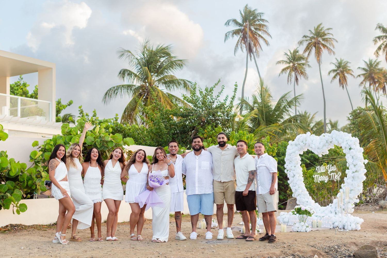Marriage proposal. Man, woman, witnesses, and  decorative setup with white flower heart overlooking the ocean in Río Grande, Puerto Rico.