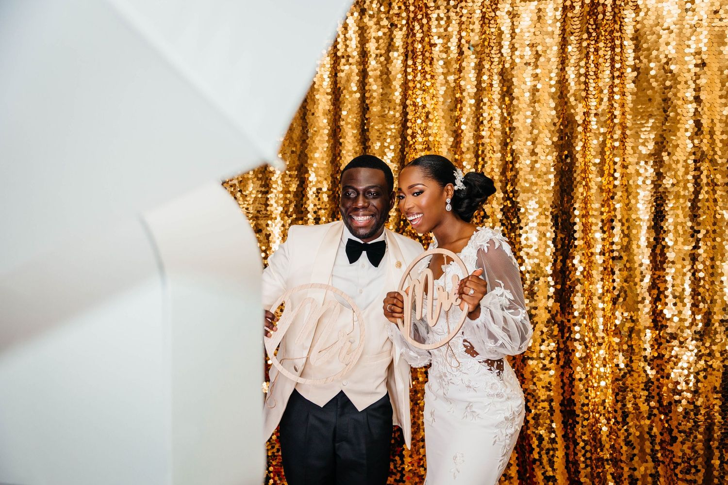 Couple celebrating joyfully against a sparkling gold sequin backdrop.