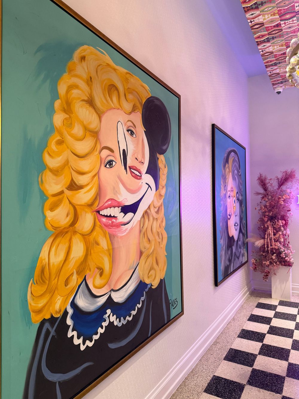 A hallway featuring a large colorful painting of a blonde woman with an exaggerated smile on a teal background.