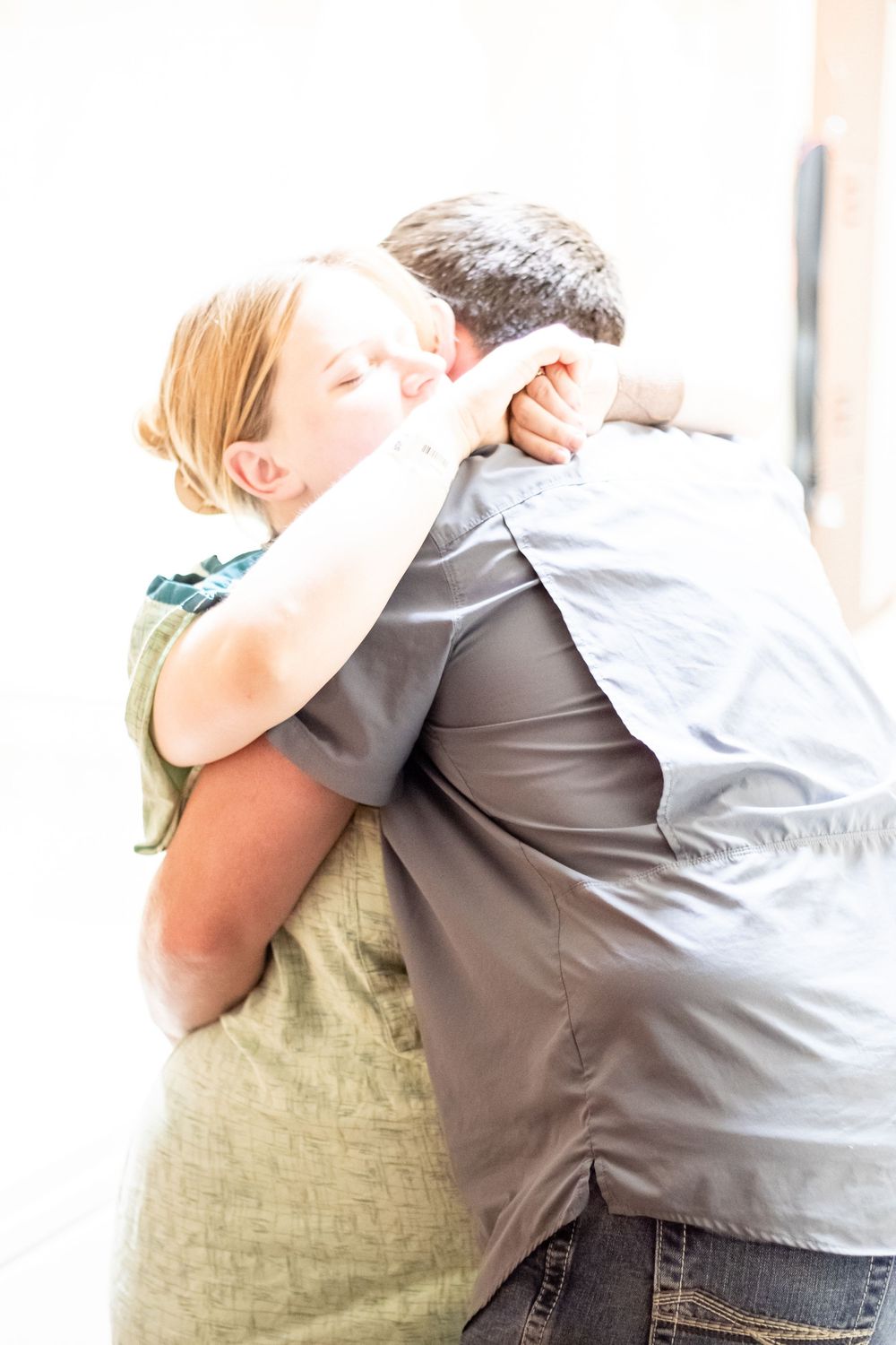 A couple shares a tender emotional hug in a bright indoor setting.