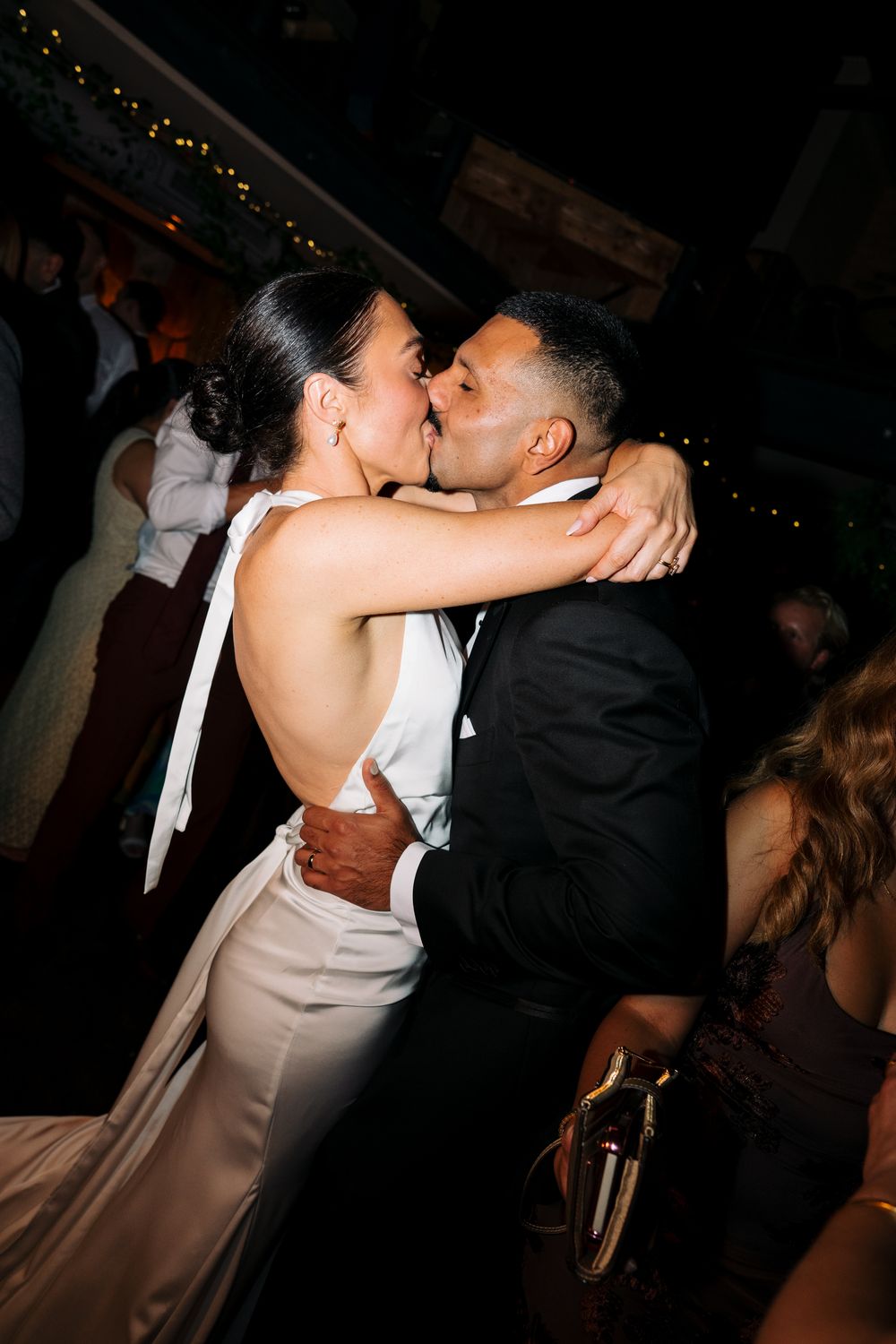 Bride and groom share a passionate kiss on the dance floor during their wedding reception.