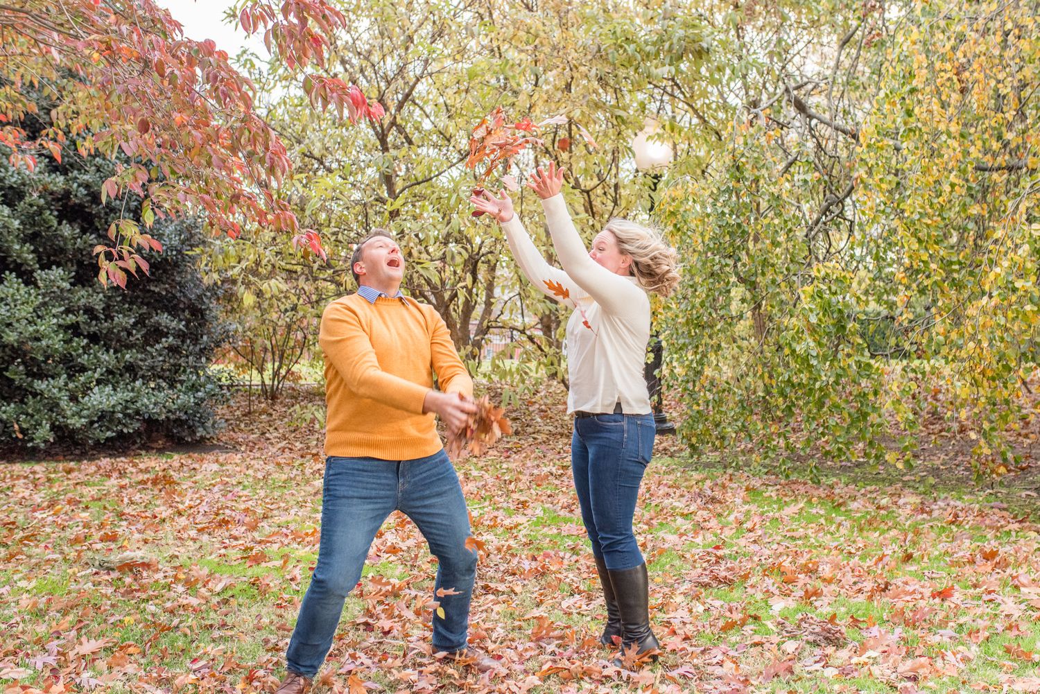 parents playfully tossing leaves in the air during a candid fall family photography session in Washington, DC
