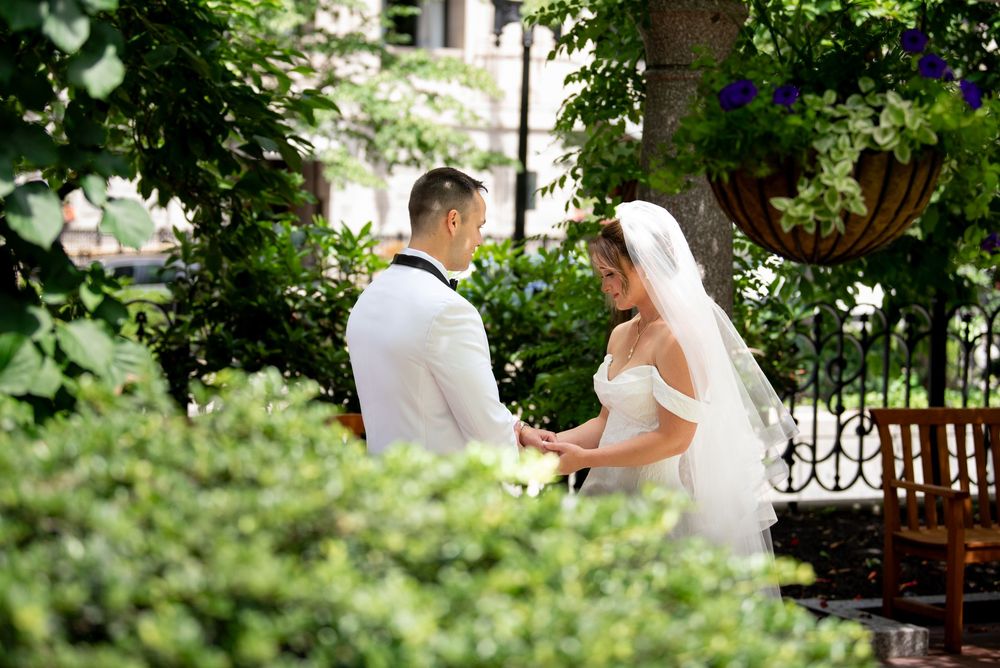 Bride and groom exchange vows outdoors surrounded by lush green foliage in a romantic garden wedding ceremony.