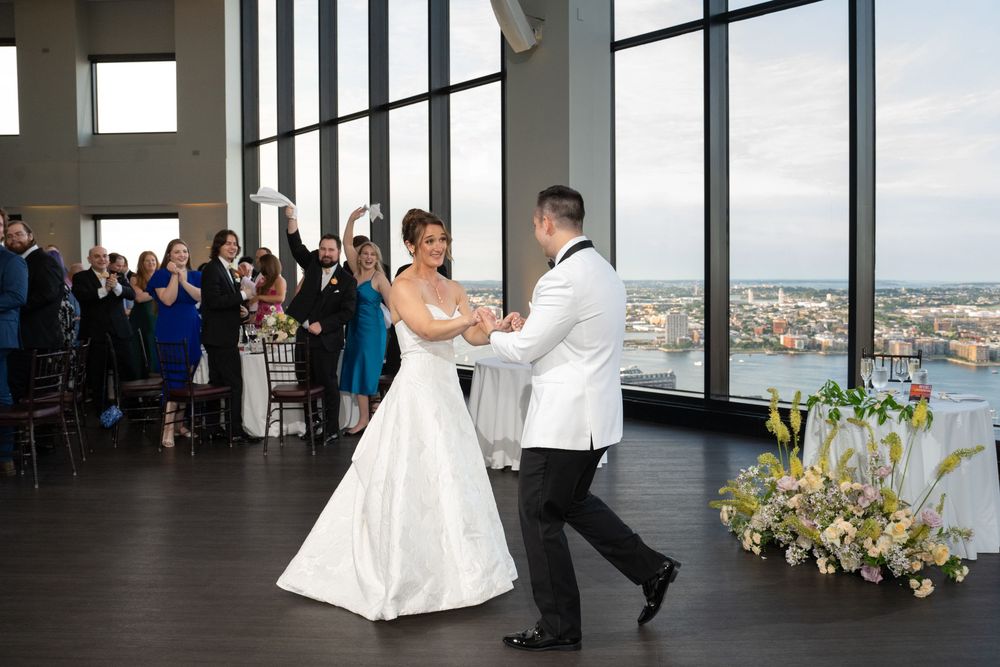 Bride and groom share first dance at elegant high-rise wedding venue with stunning waterfront views.