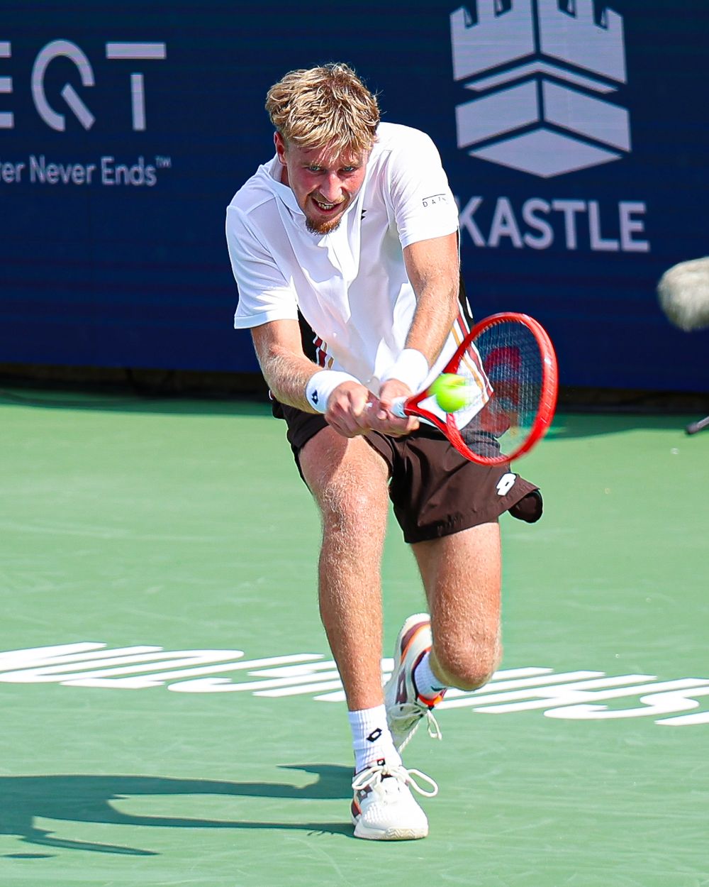 Tennis player executing a powerful backhand shot on an outdoor court during a professional match.