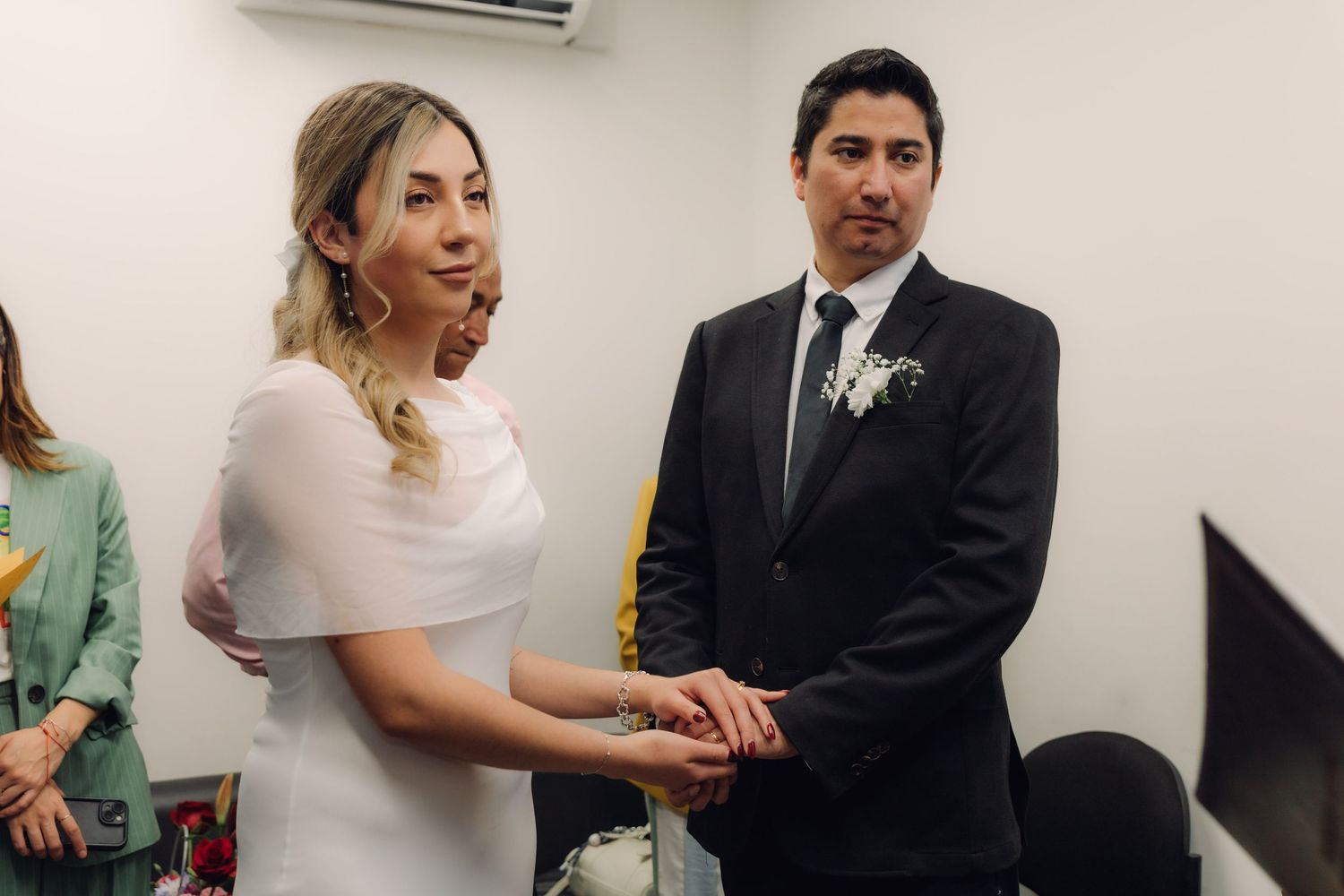 Bride and groom holding hands and exchanging vows during an intimate indoor civil wedding ceremony.