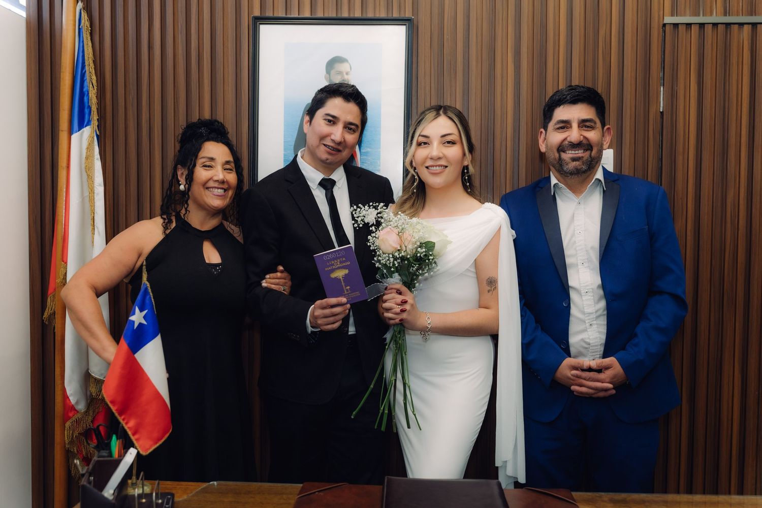 Newlywed couple posing with two witnesses holding marriage booklet at Chilean civil wedding.