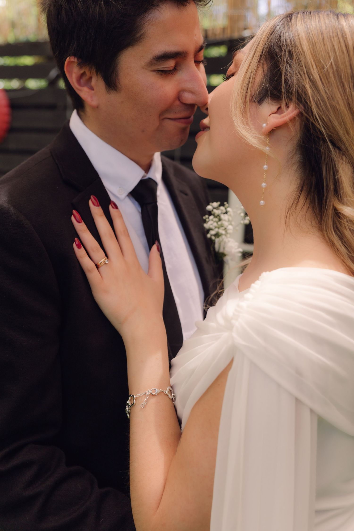 Bride and groom sharing a romantic moment, nearly kissing, bride's hand resting on groom's chest.