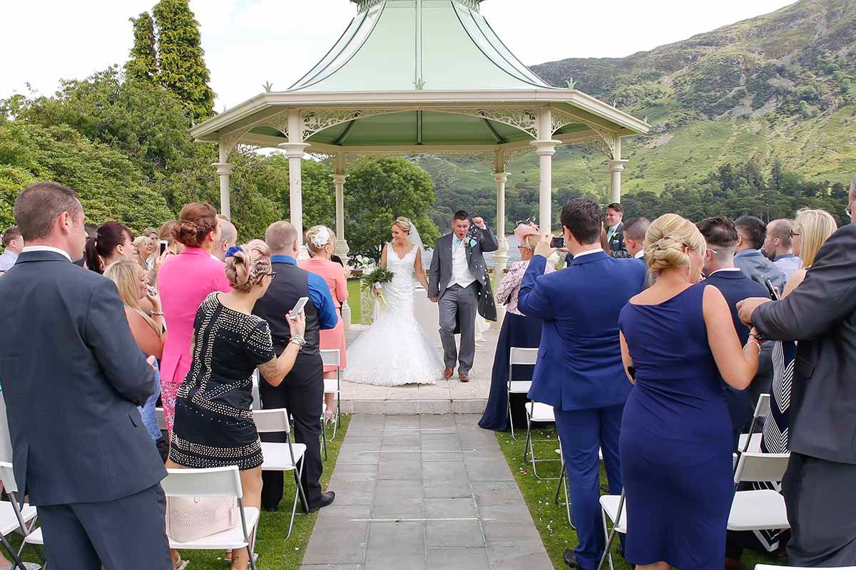 Bride and groom walk down the aisle at the outside gazebo at the Inn on the Lake - Glenridding