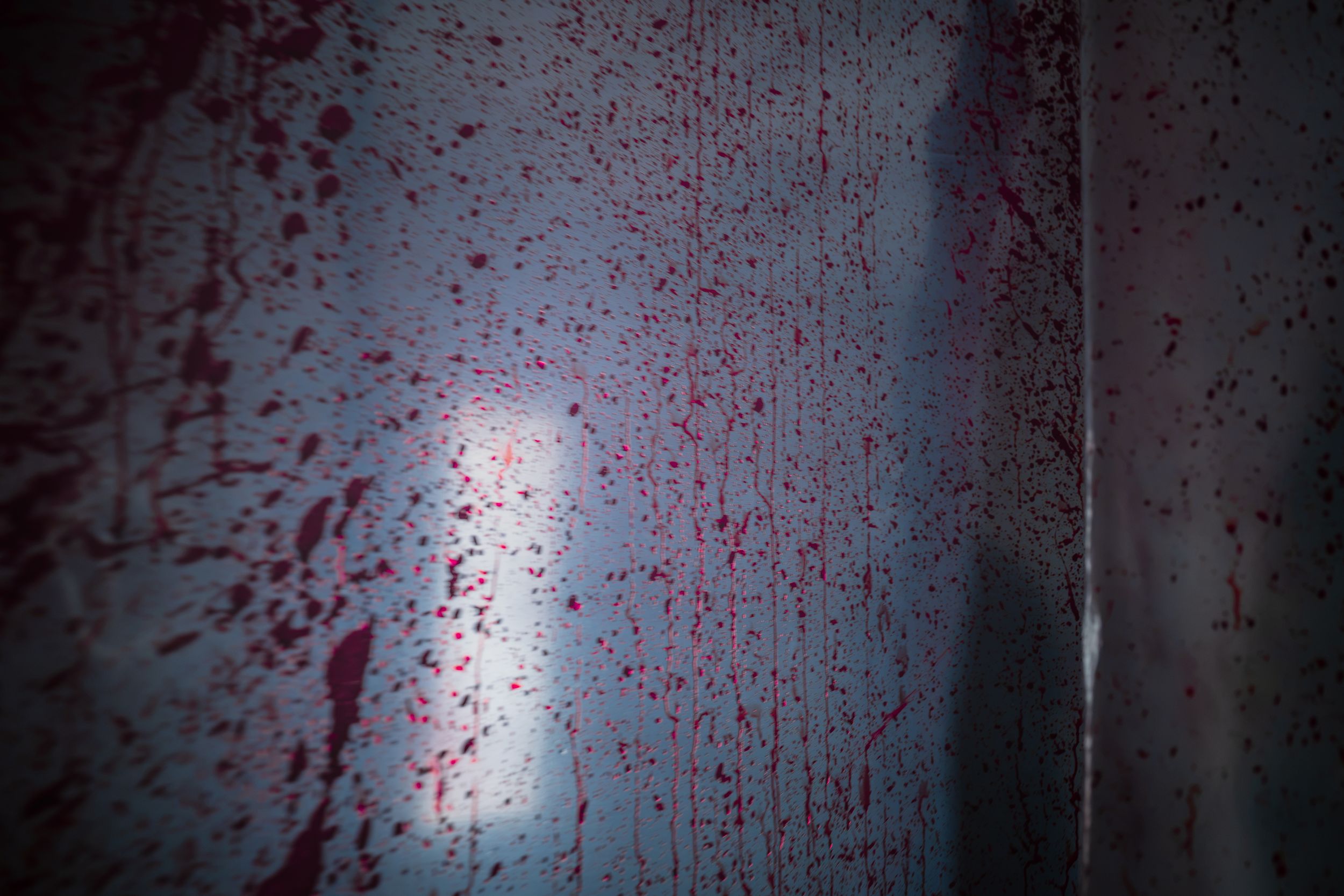 Dark wall splattered with red blood stains, creating a dramatic horror scene effect.