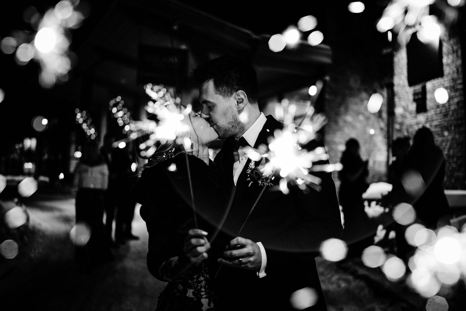 Black and white sparkler kiss with glowing bokeh at a Canmore winter wedding