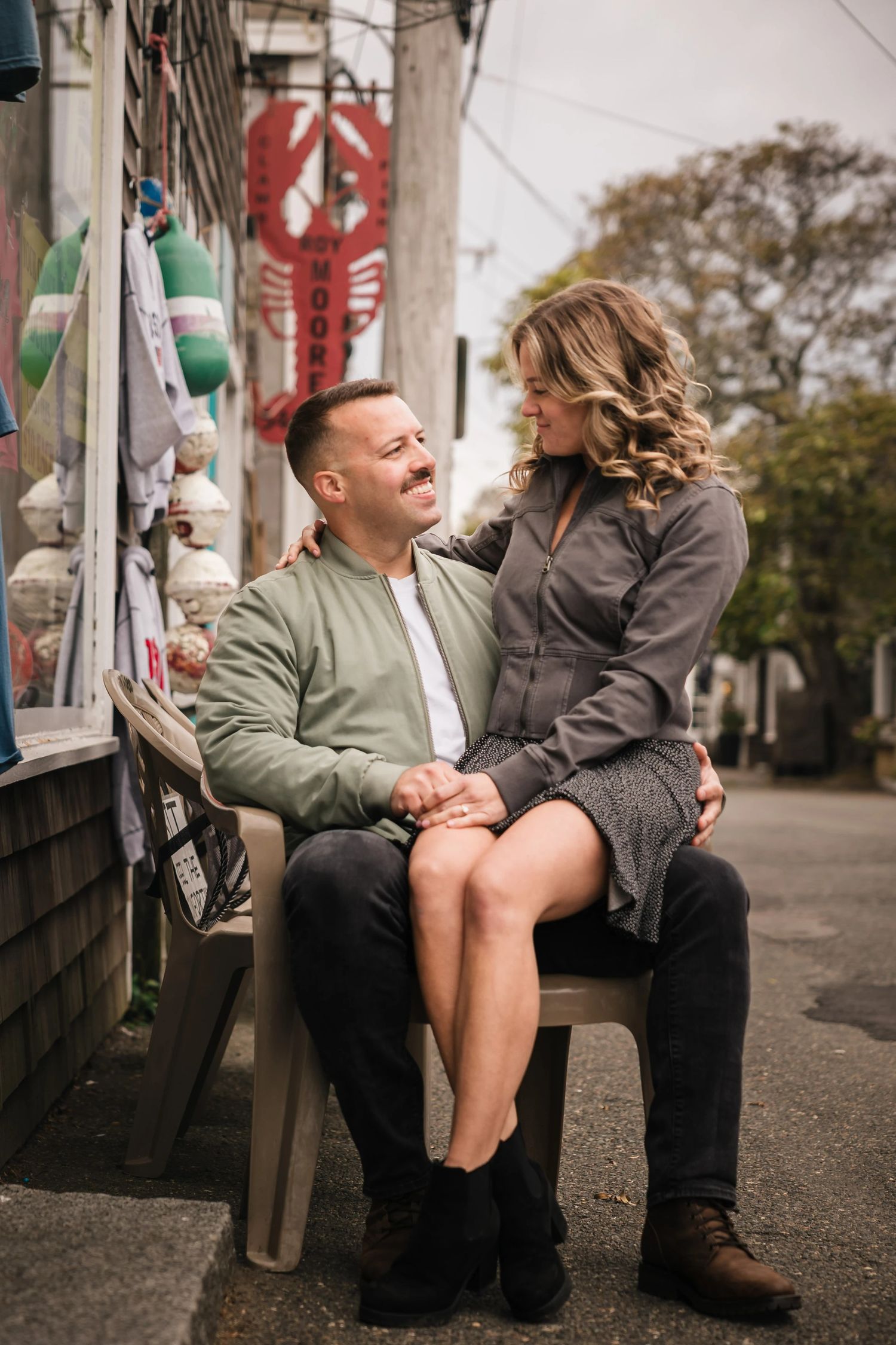 Man and woman sitting together on a food truck step, facing each other in an intimate moment. Engagement at Rockport Harbor, Rockport, MA