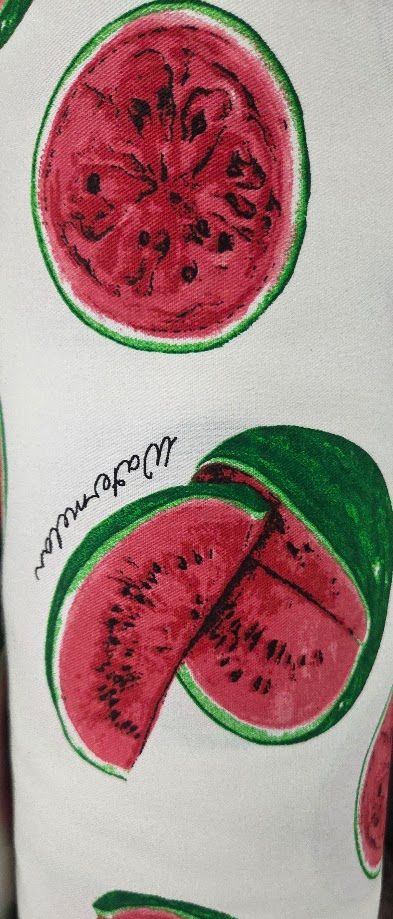 White fabric featuring vibrant watermelon print with sliced and whole watermelons in red, green, and black.