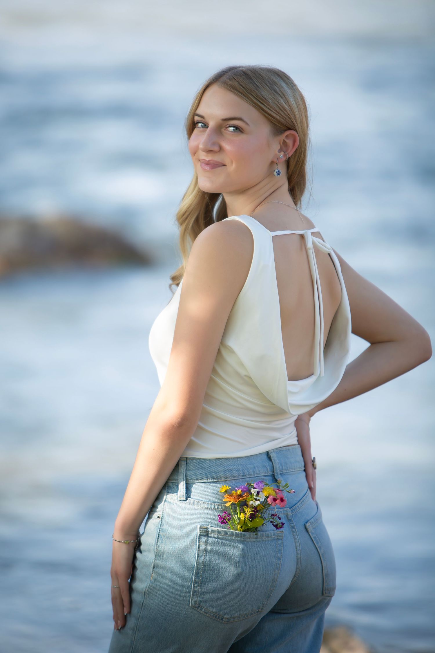 girl wearing jeans and a white top with wildflowers in back pocket