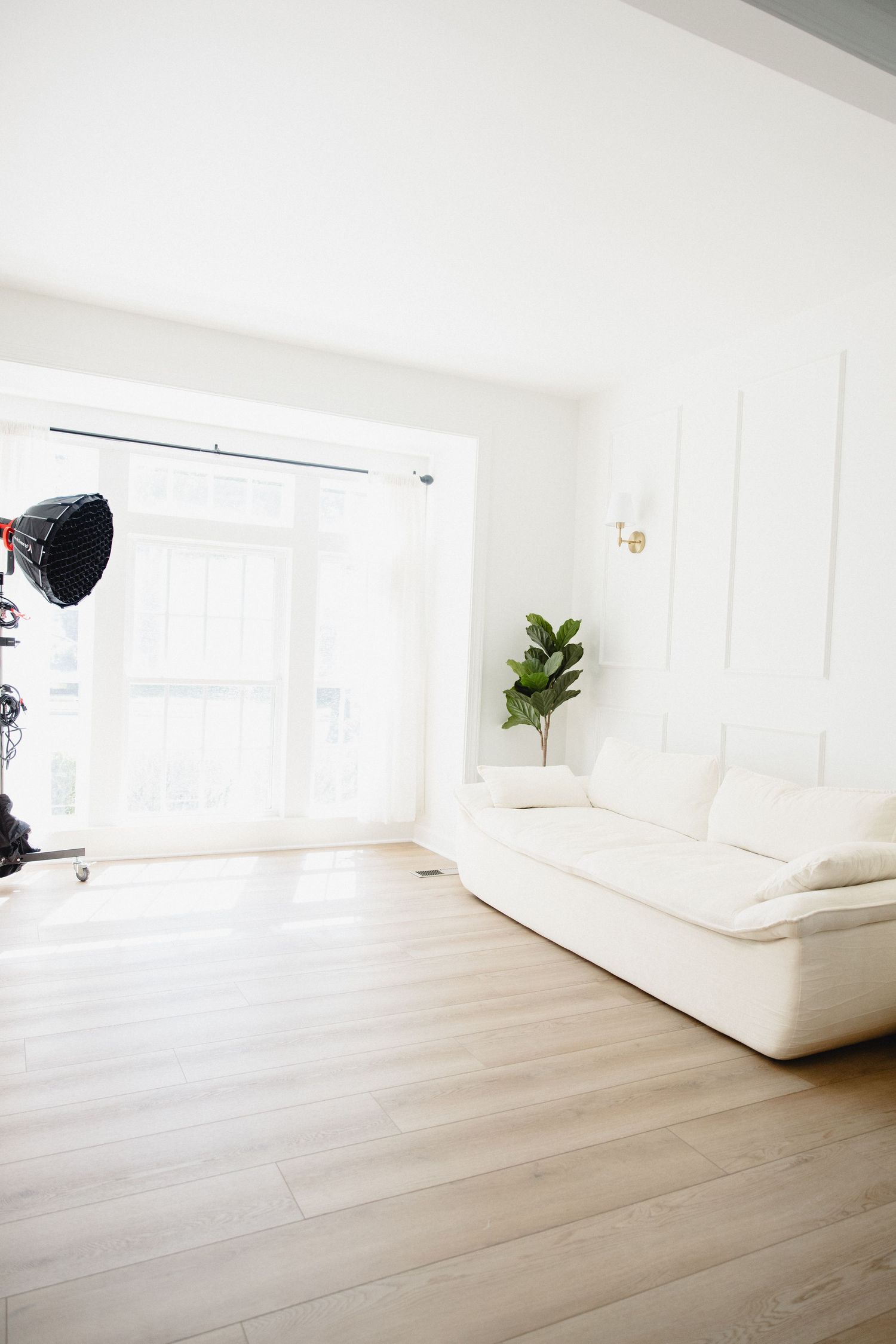Couple relaxing on white sofa with camera and filming equipment in bright modern living room.