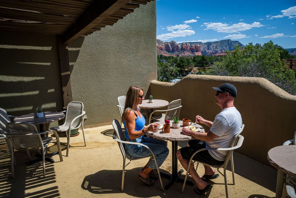A couple enjoying breakfast with red rock views at a luxury hotel, The Southwest Inn in Sedona, AZ.