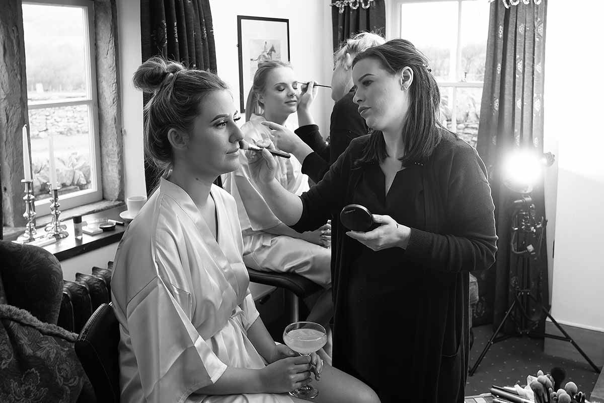Make up artist apply finishing touches to bridesmaid at New House Farm wedding venue Lorton Cockermouth