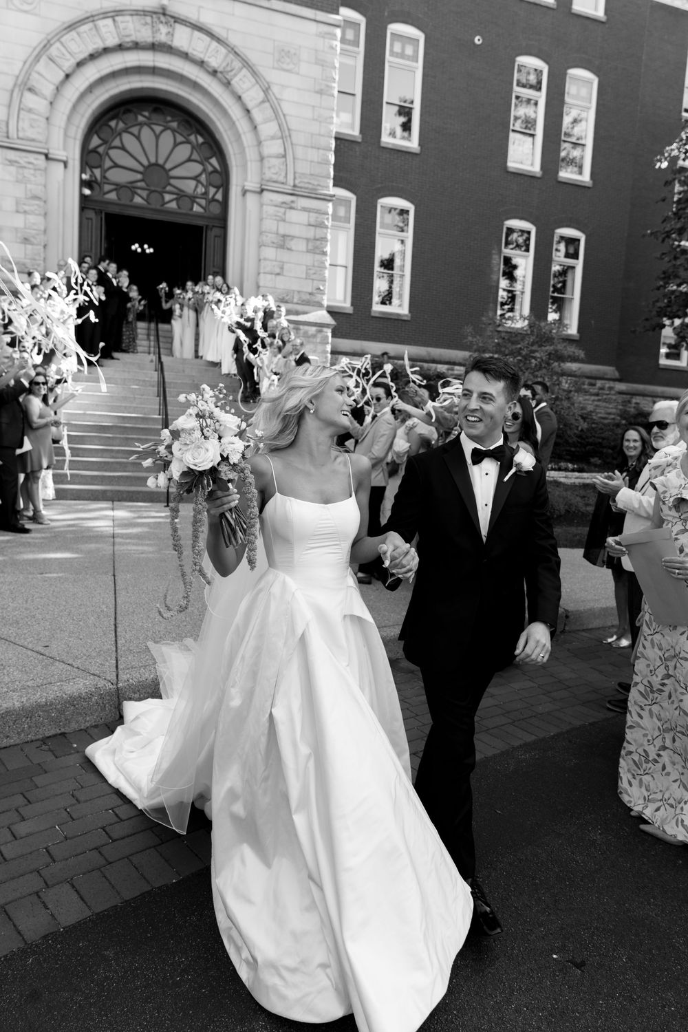 Bride and groom exiting church ceremony in black and white wedding portrait.