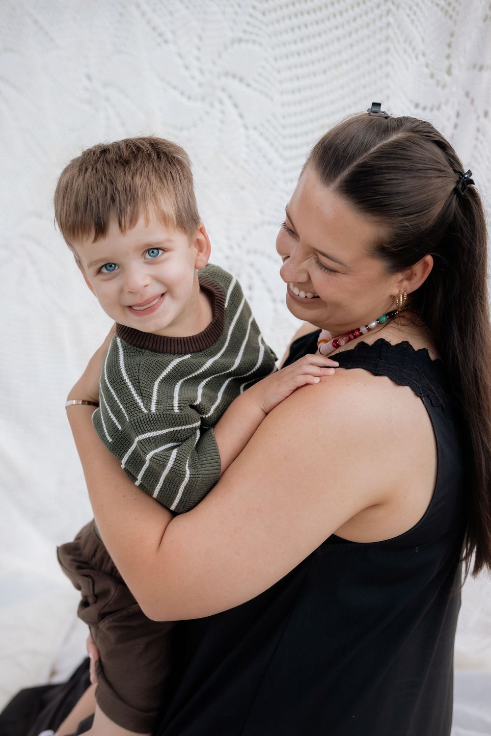 Joyful candid moments between child in striped shirt and woman in black top.