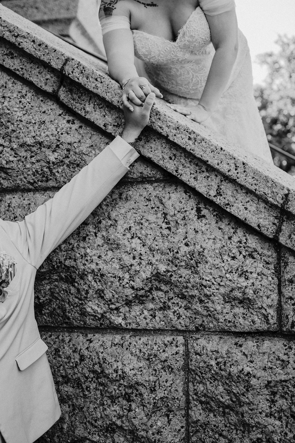 Black-and-white photograph of newlyweds holding hands across a stone wall outside the Tarrant County Courthouse in Fort Worth.