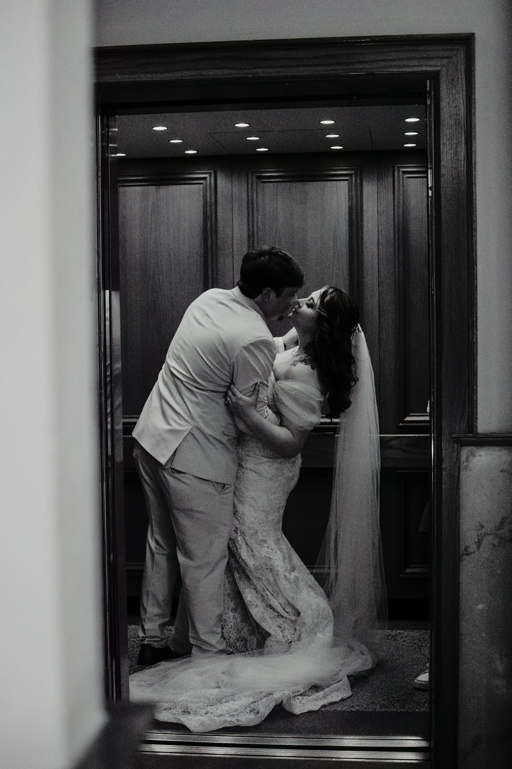 Black-and-white photograph of newlyweds kissing inside an elevator during their Fort Worth courthouse wedding portraits.
