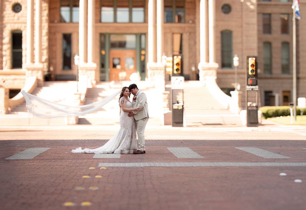 Newlyweds kiss in a downtown Fort Worth crosswalk near the courthouse as the bride's long veil moves in the wind.