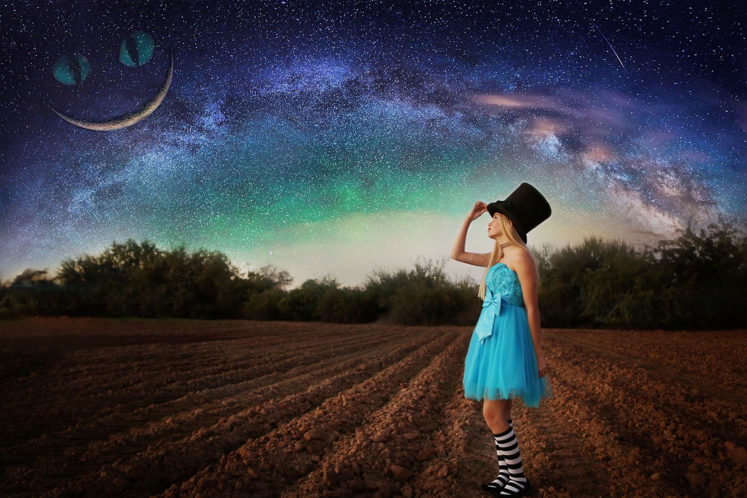 A girl in a turquoise dress and black top hat gazes up at a starry Milky Way sky above a plowed field.