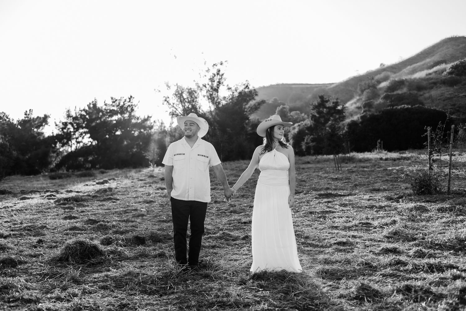 Happy couple embracing on a wooden bridge surrounded by lush green trees in a romantic outdoor setting.