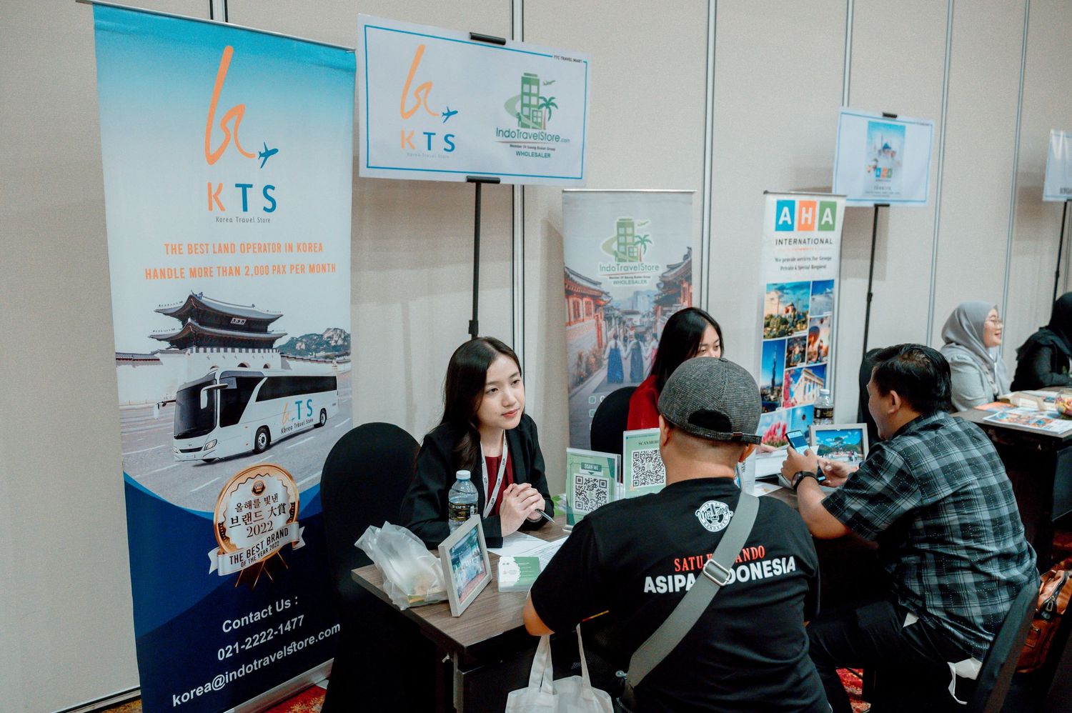 Travel expo booth with NTS tourism banner, attendees discussing packages at ASIPA Indonesia event.