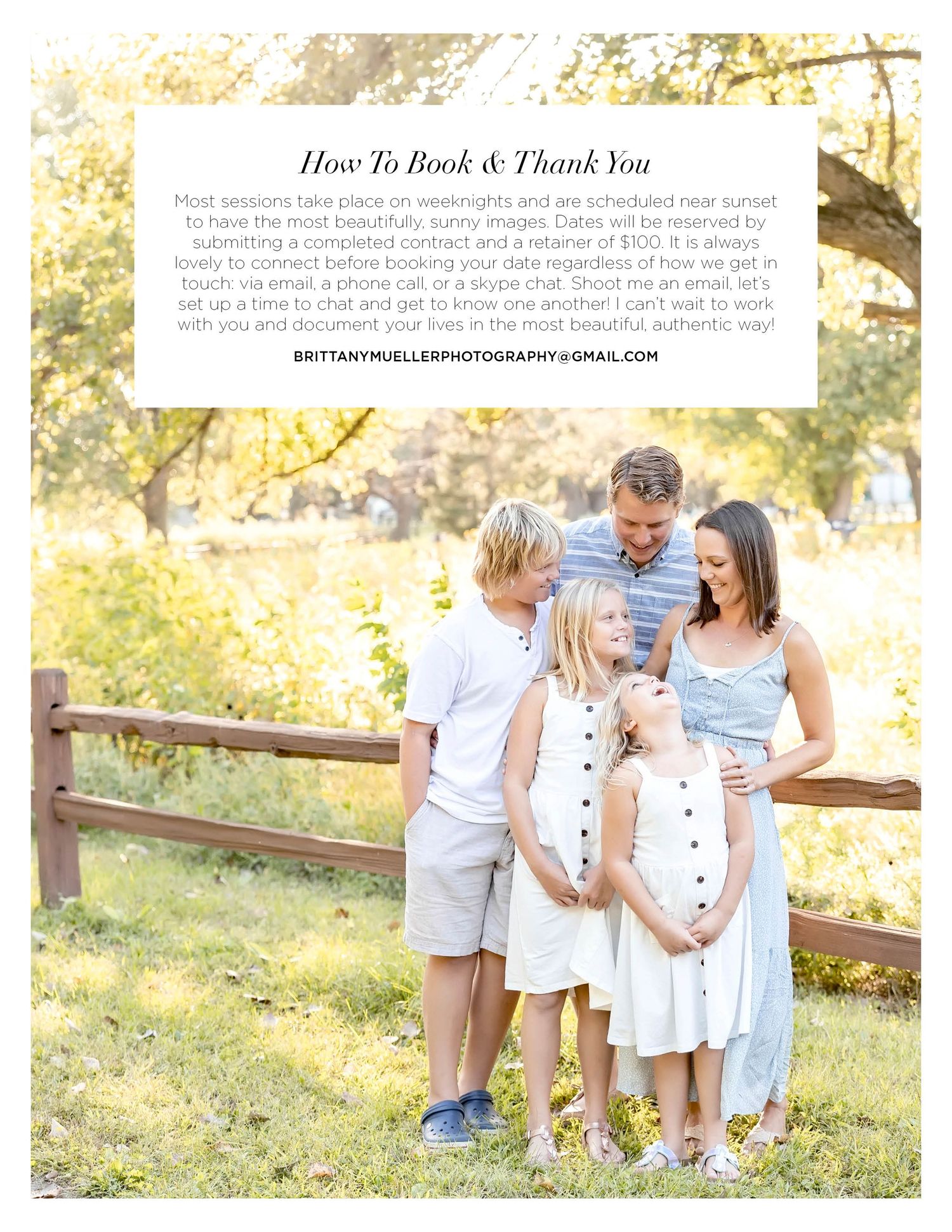 A happy family of four poses outdoors near a wooden fence, dressed in white and blue outfits, for a professional photography session.