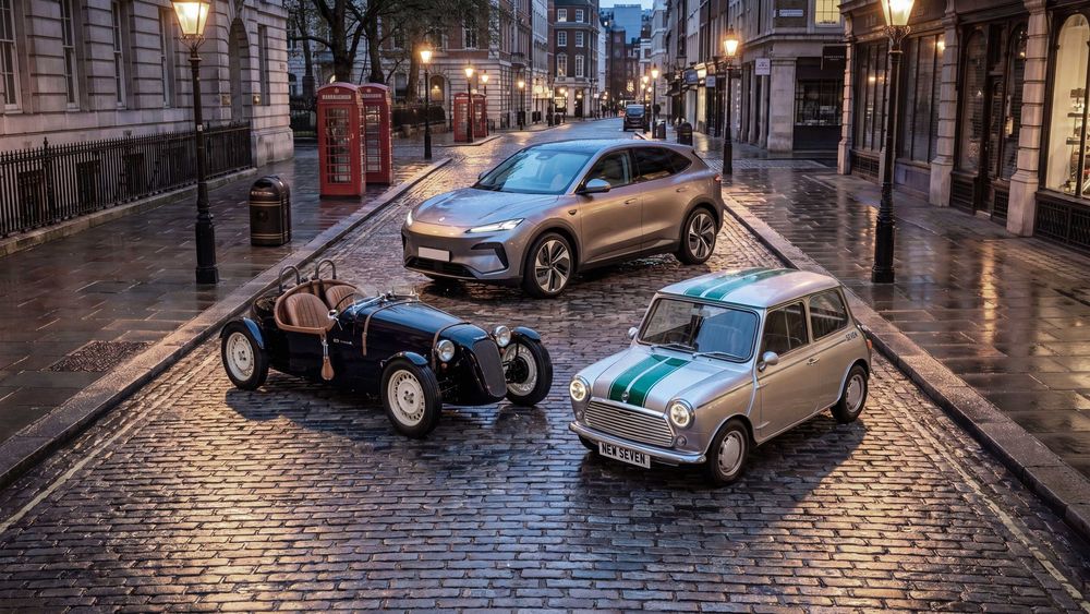 Three classic and modern electric cars parked on wet cobblestone street at dusk with glowing lampposts in urban setting.