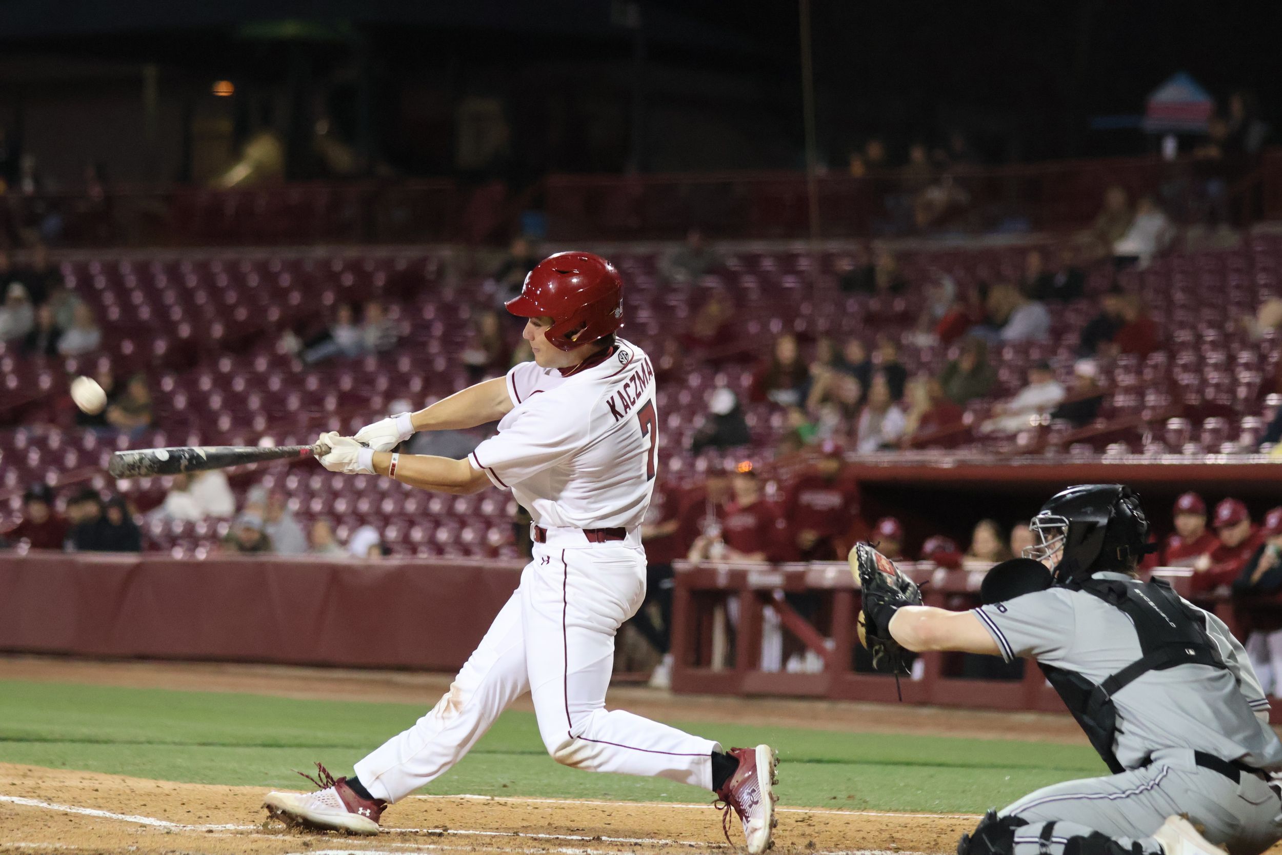 South Carolina baseball batter connects with a pitch as the catcher reaches forward.