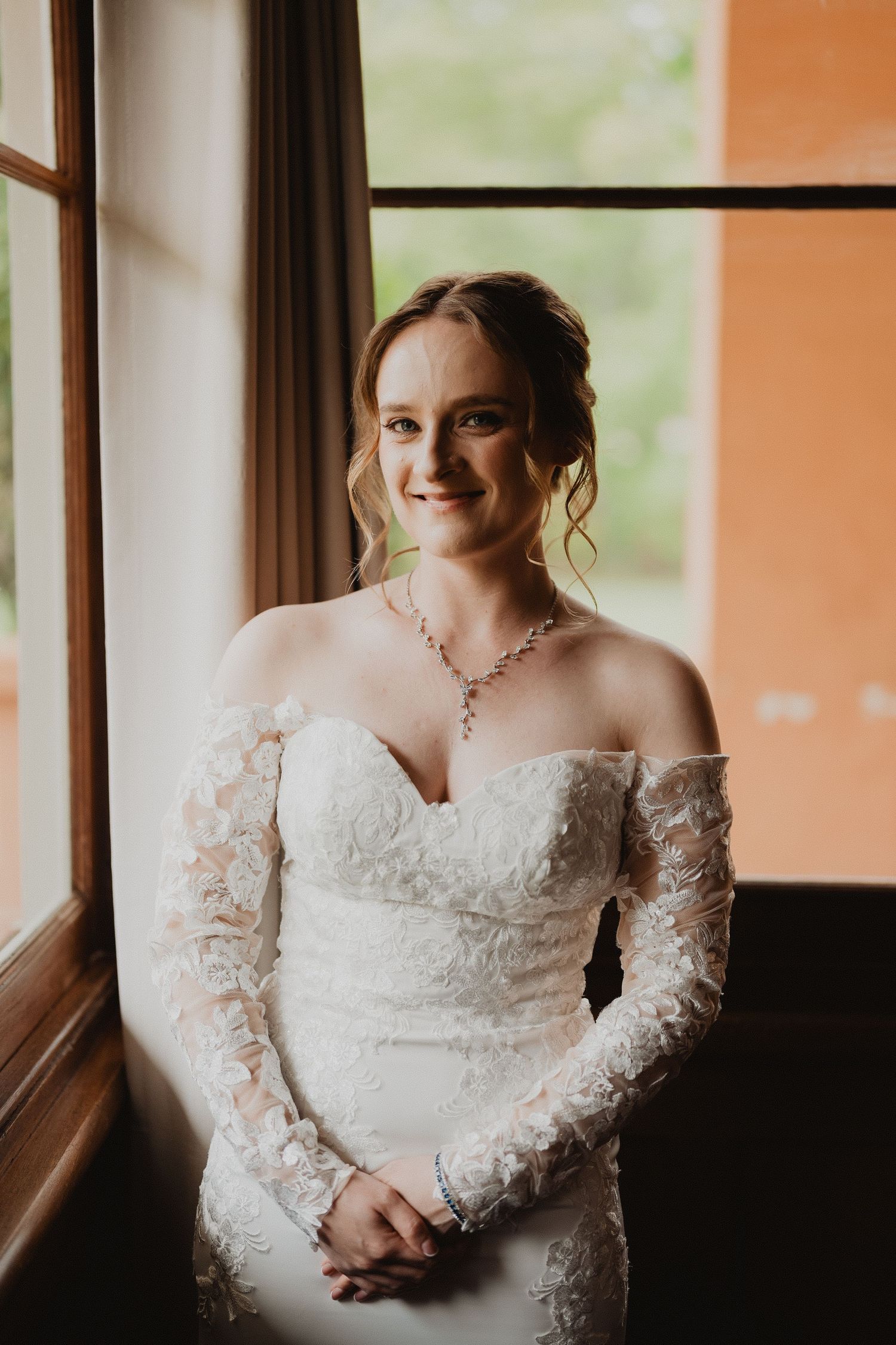 Lucy in her lace wedding dress by the window