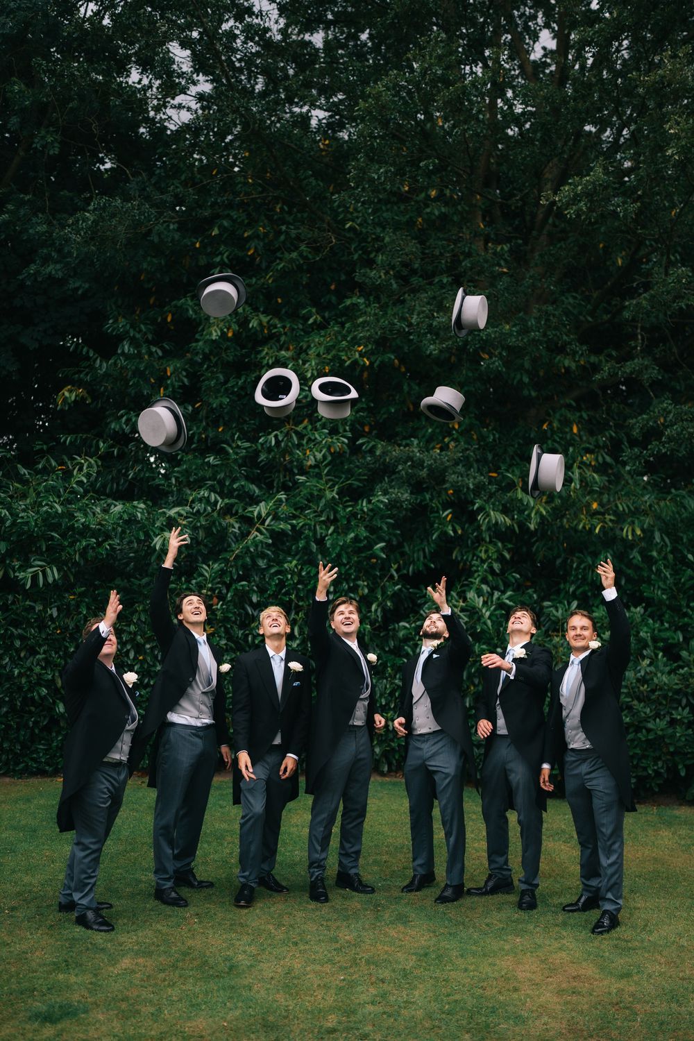 A sequence of groomsmen in black suits tossing their hats in the air during a wedding photo session, Pendrell Hall, Wolverhampton