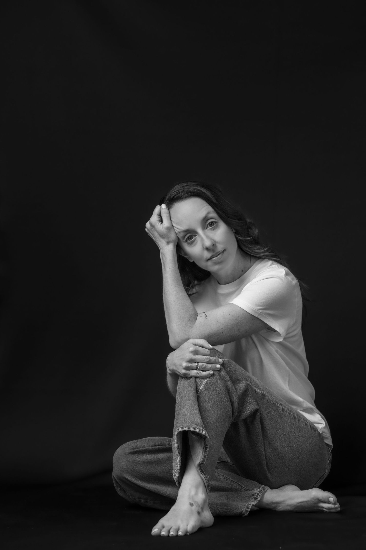 Black and white portrait of a woman resting her chin on her hands, gazing thoughtfully at the camera. Best photographer Williamsburg VA