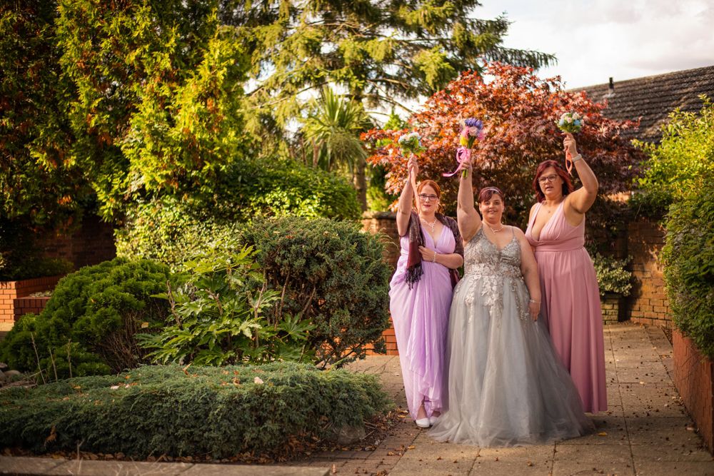 Celebration scene with bridesmaids in purple and pink dresses in a garden setting.