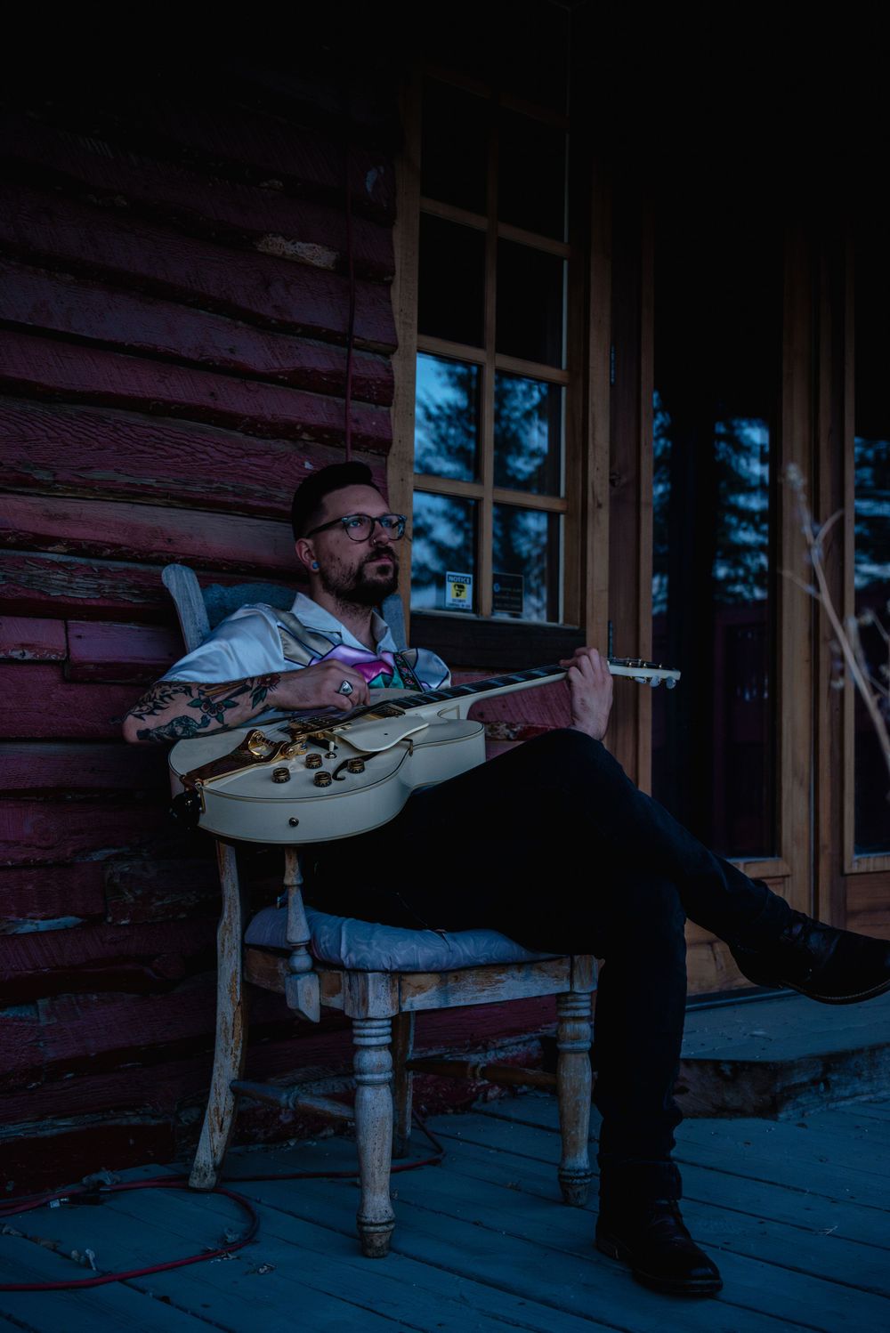 Outdoor male musician branding shoot during blue hour, holding a guitar with raw, authentic vibes.