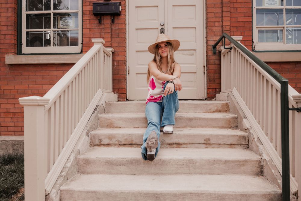 Western fashion shoot featuring trendy pink cow print silk top and stylish boots.