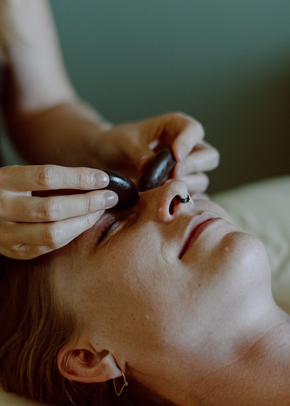 Personal branding shoot of a massage therapist using facial stones, highlighting relaxation and wellness.